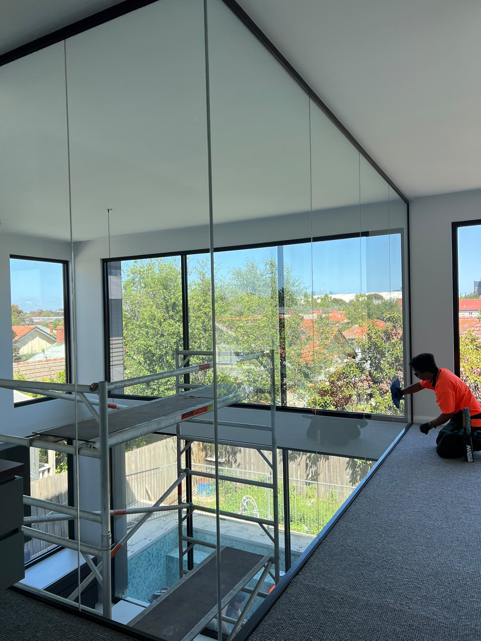 Interior glass wall being cleaned beside scaffolding