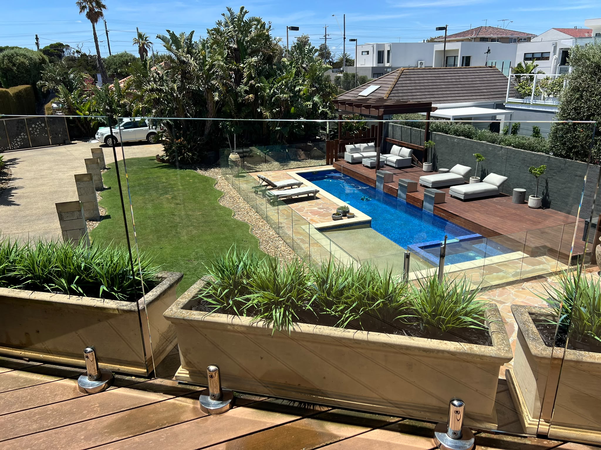 Clean frameless glass pool fence overlooking a landscaped pool