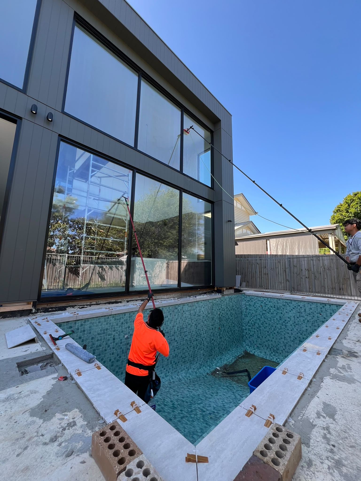 Pristine Sheen team cleaning large windows on a modern home