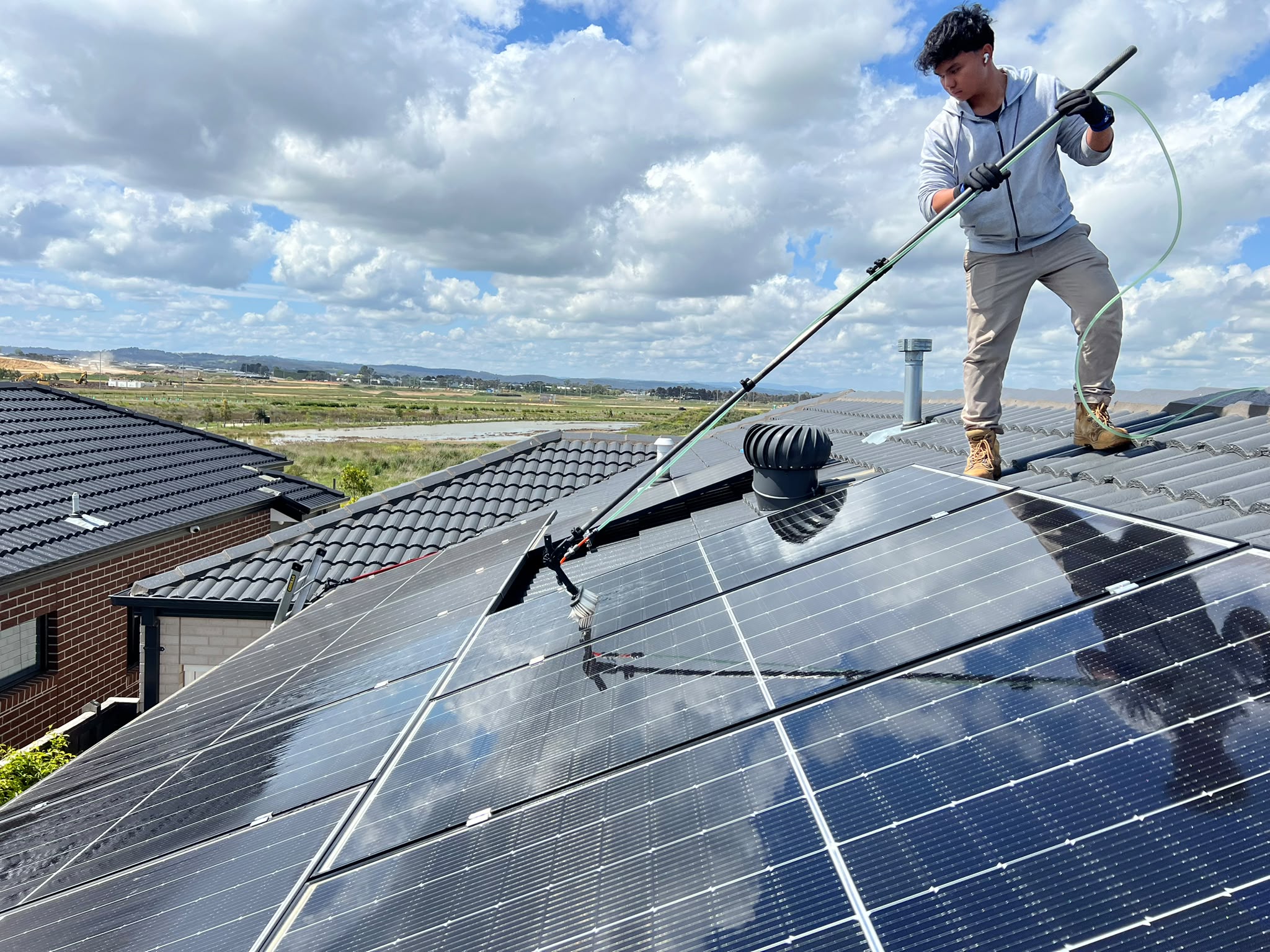 Pristine Sheen team member cleaning rooftop solar panels